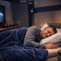 Traveler resting on a modern lie-flat business class seat during a long-haul flight.