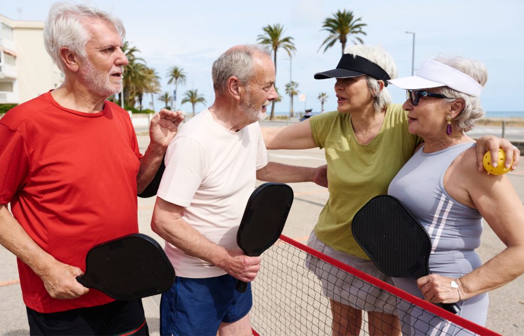 Players enjoy a doubles pickleball game on a shaded resort court